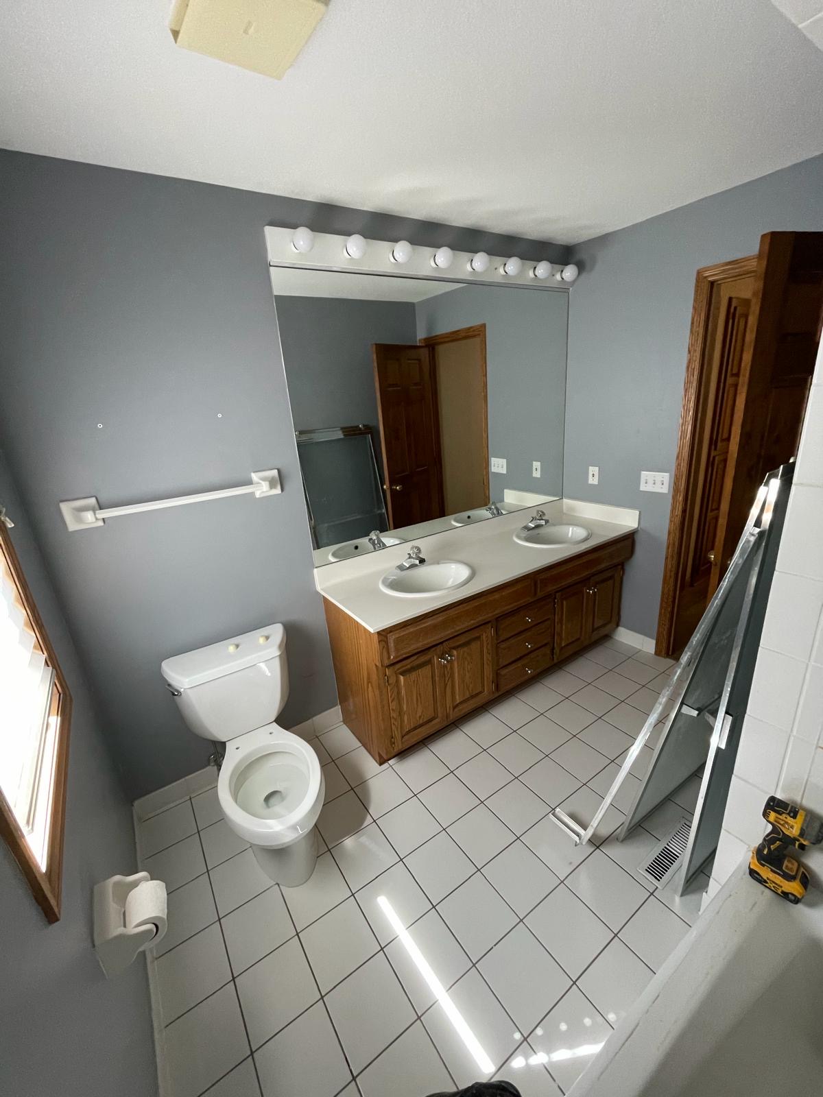 Dated bathroom with oak vanity and white tile floor before update