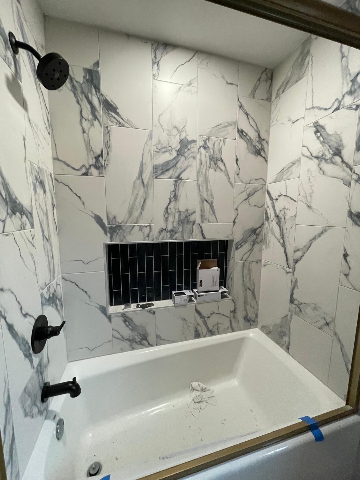 New marble-look tile surround with black tiled niche