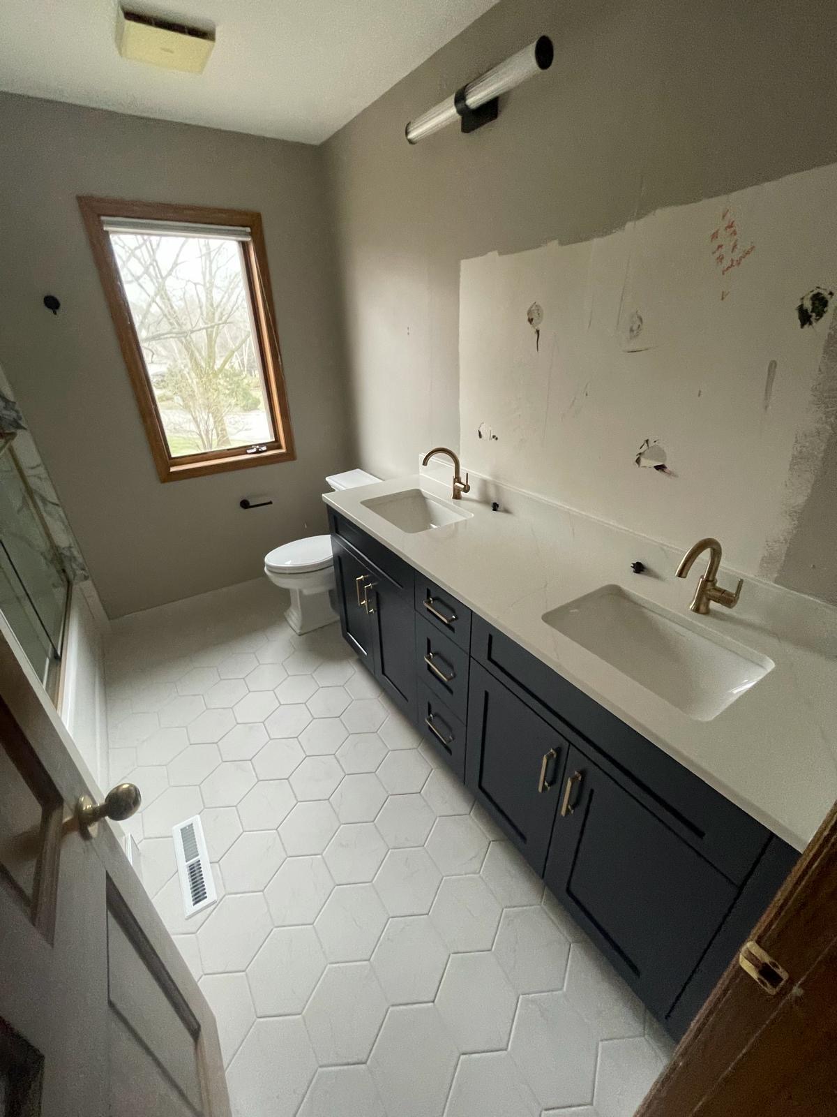 Updated bathroom with navy vanity, quartz top and hex tile floor